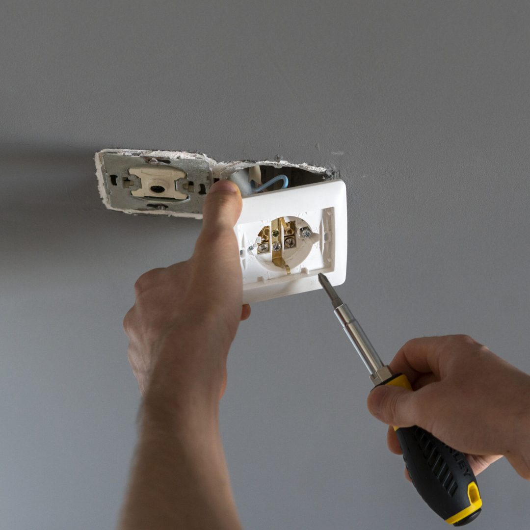 handyman fixing the electricity power socket in the wall at home